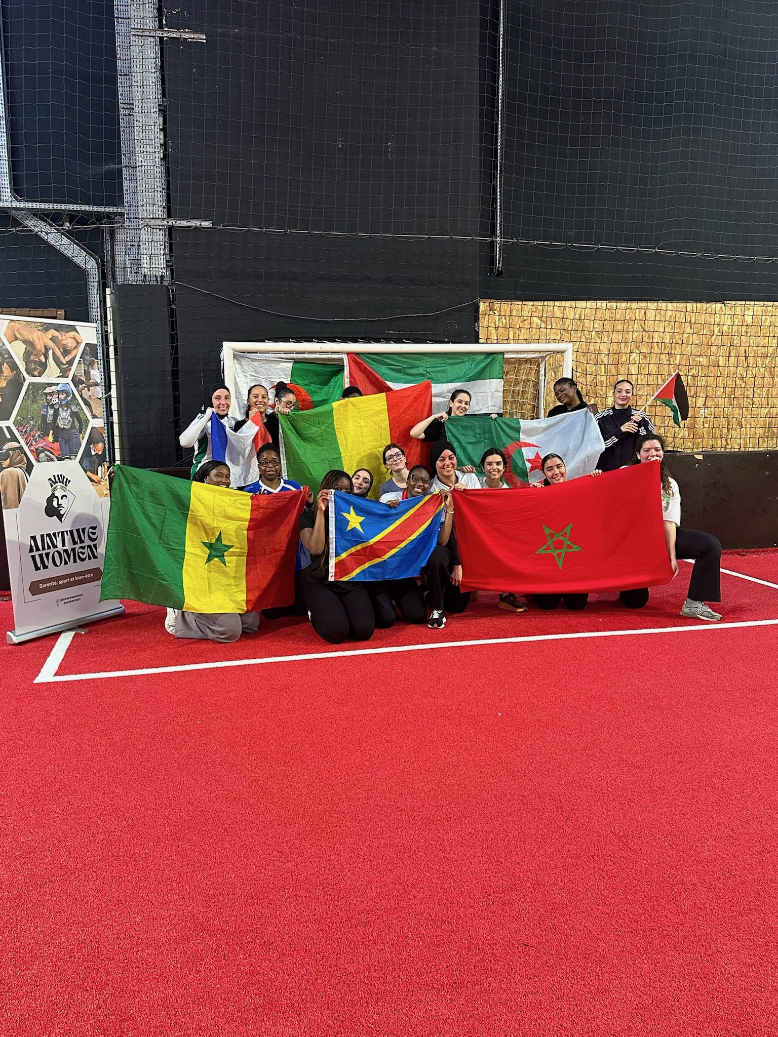 Groupe célébrant avec des drapeaux sur un terrain de foot en salle